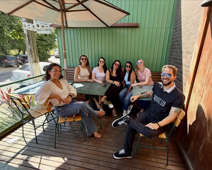 Grupo sentado à mesa na calçada da Padoca, embaixo do guarda-sol, no café da manhã depois de uma defesa de doutorado.