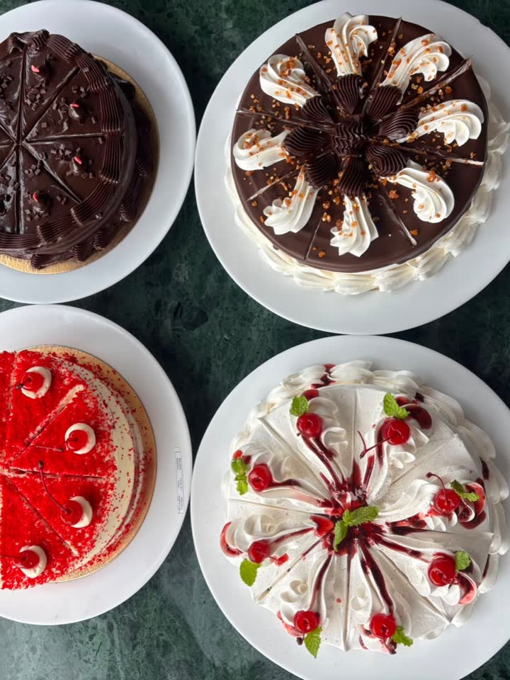 Quatro tortas inteiras da Padoca vistas de cima: chocolate, chantilly com cerejas, morango e uma de creme com raspas.
